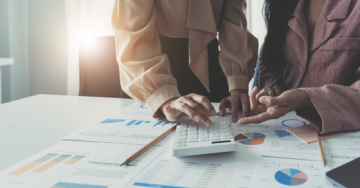 Two people reviewing reports a pointing at a calculator