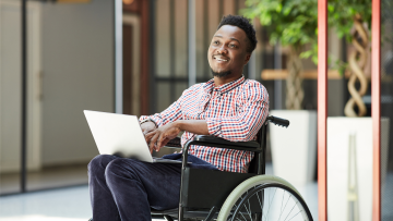 man in a wheelchair using a laptop
