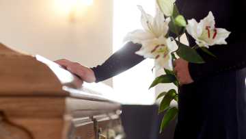 mourner holding lilies at a casket