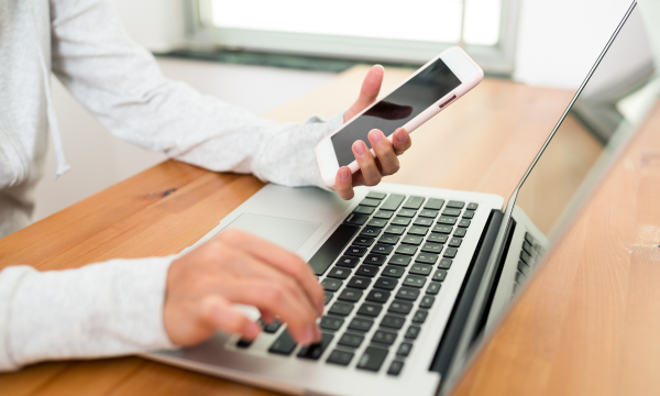 woman using a phone and laptop