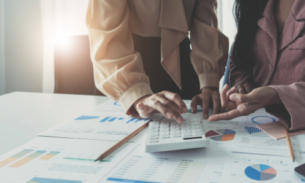 Two people reviewing reports a pointing at a calculator