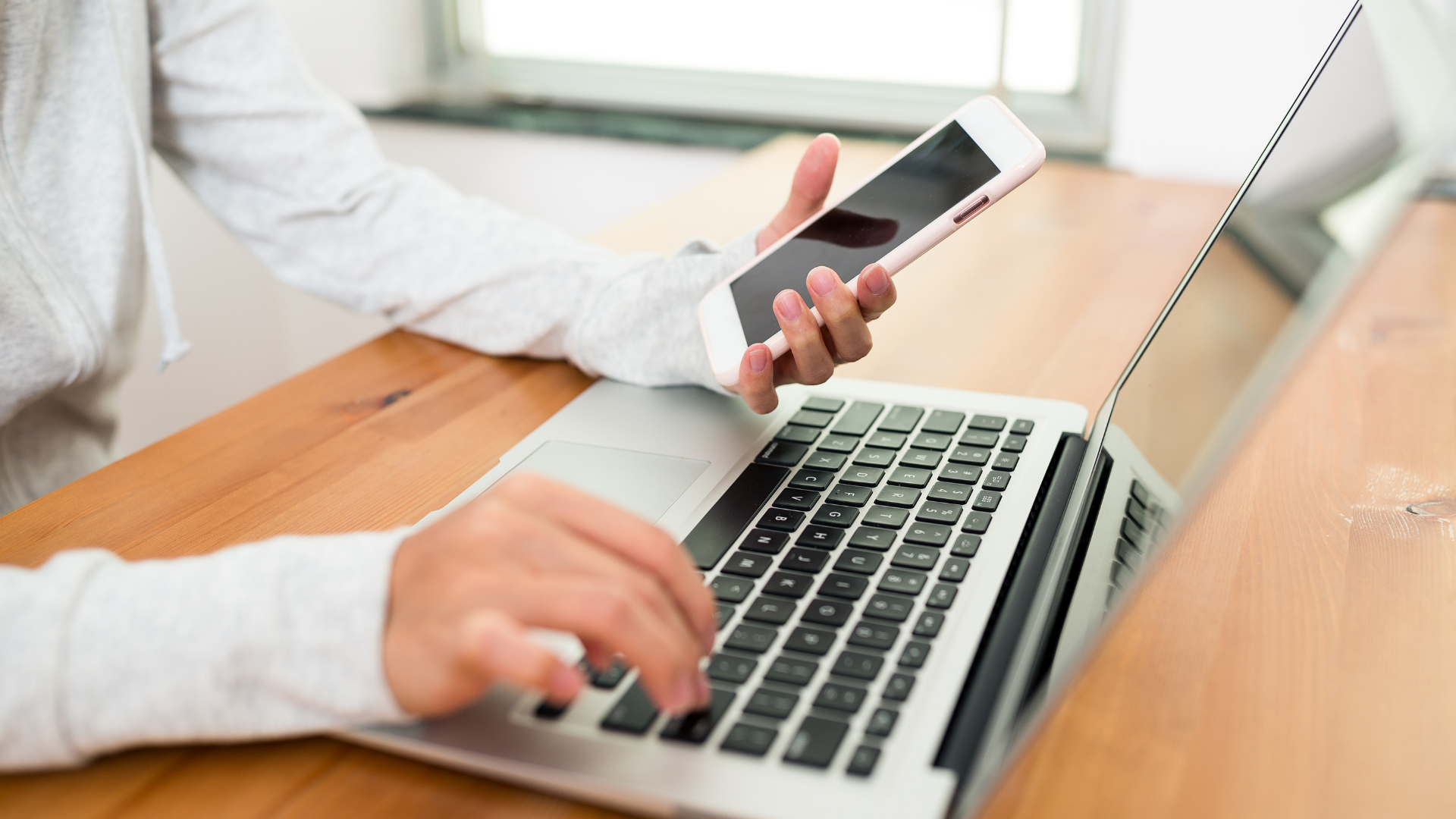 woman using a phone and laptop