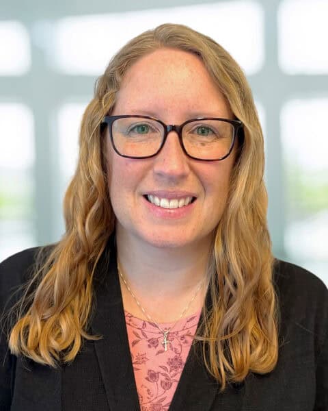 Professional portrait of a woman CPA at SEK with glasses and long wavy hair.