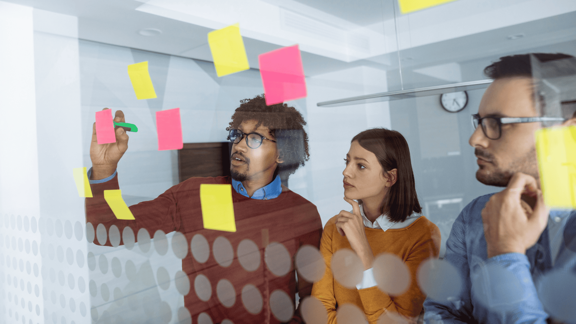 group of three individuals looking at sticky notes