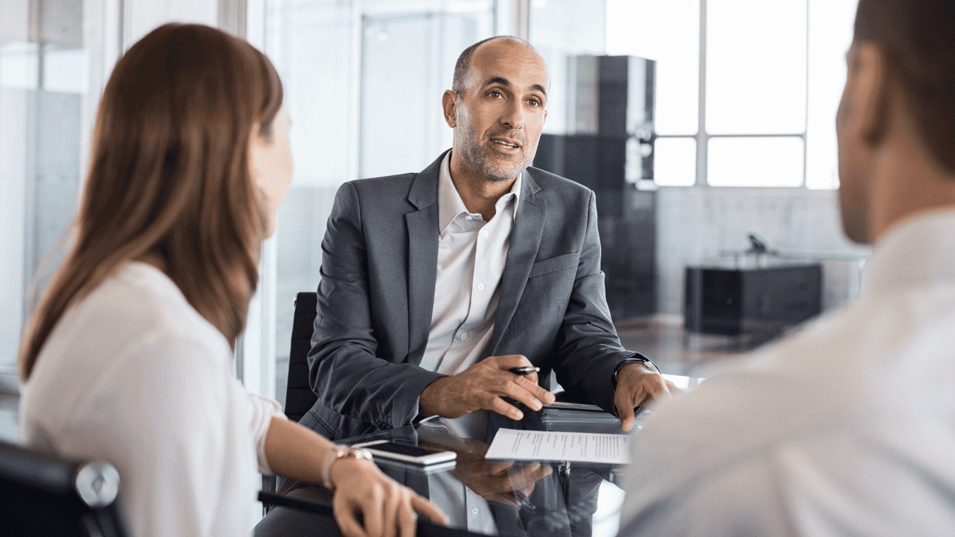 two men and a woman meeting around a desk