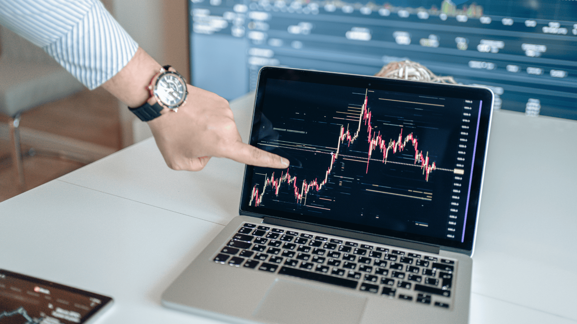 man pointing to laptop with stock chart
