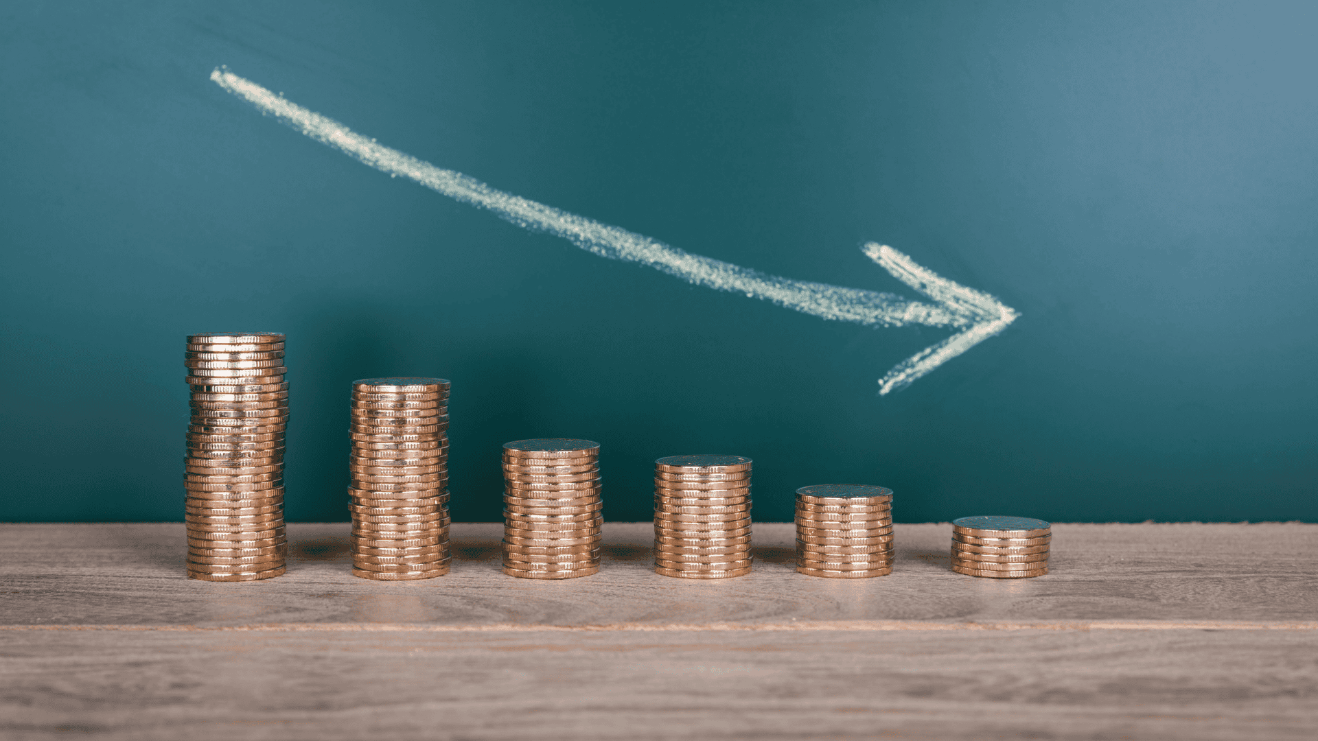 coins stacked in front of an arrow pointed downward