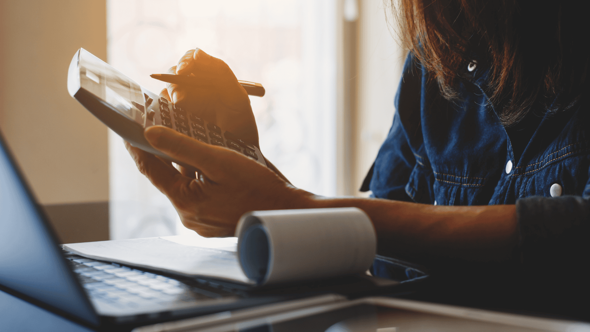 Woman at desk holding calculator and pen