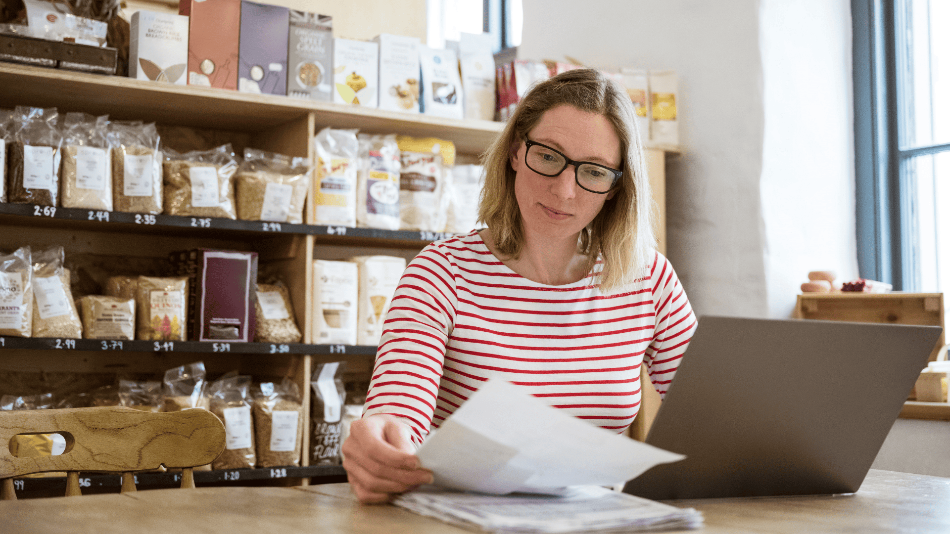 woman in red and white striped top reviewing papers at desk in a store