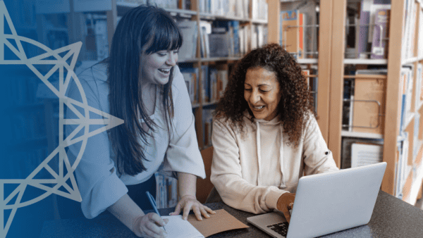 Two women in a library looking at a laptop